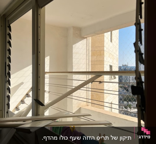 תריסים שבורים על חלון עם חבלים לתליית כביסה